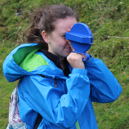 Girl in a blue coat using equipment to do geography fieldwork