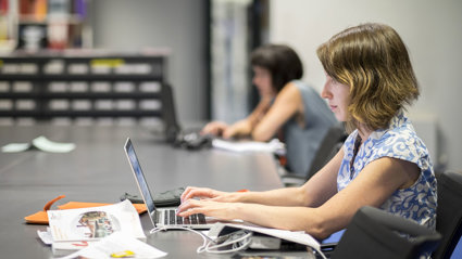 Person at a large table typing on a laptop.
