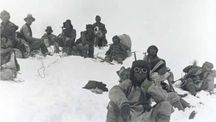 Historic black and white photograph of Sherpa climbers with mountaineering equipment on Mount Everest.