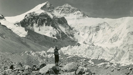 Old black and white photograph of a person taking a picture of Mount Everest.