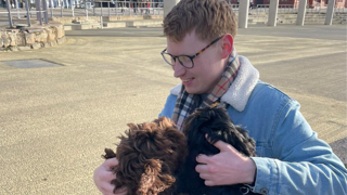 Paul Logue holding two dogs and looking at them with endearment.