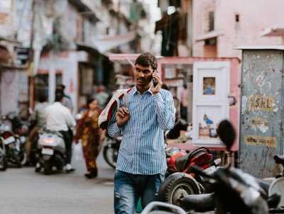 A man walking down a road with a mobile phone to his ear