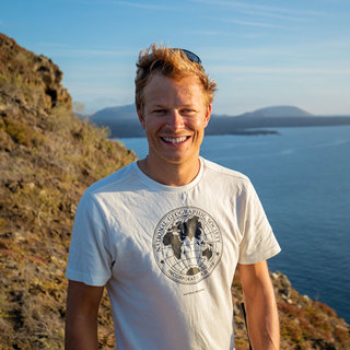 Bertie Gregory on a cliff overlooking an ocean.
