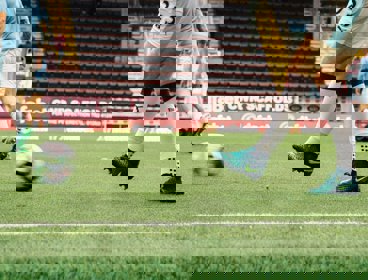 A footballer kicking a ball on a football pitch