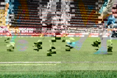A footballer kicking a ball on a football pitch
