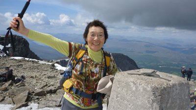 Junko Tabei on summit of Ben Nevis with view of land below.