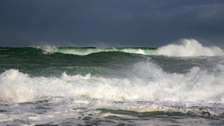 Big ocean waves under a dark, gloomy sky.