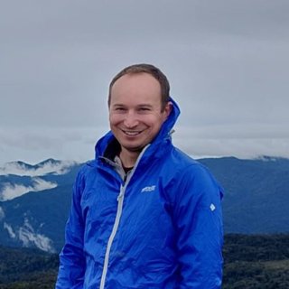 Person wearing blue coat against mountainous backdrop.