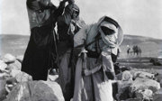 Black and white photograph showing three men drawing water from a well.