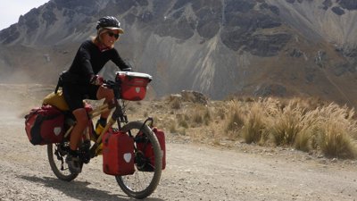 Kate Rawles cycling on a bamboo bike on a unmade road in Cordillera Blanca, Peru.