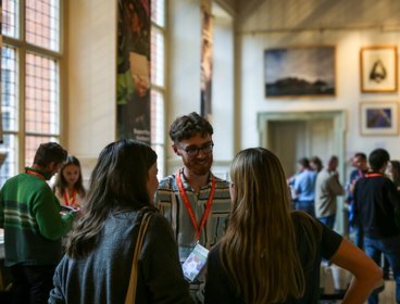 People chatting at Explore conference in historic room.