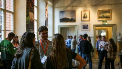 People chatting at Explore conference in historic room.