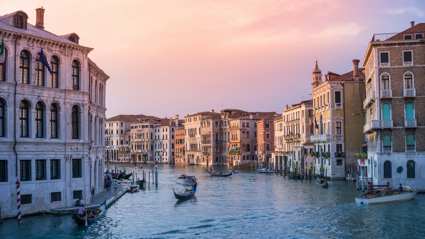 A boat sails downa cannal in in Venice as the sunsets