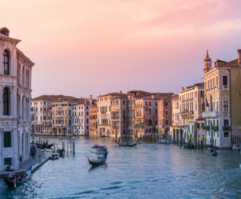A boat sails downa cannal in in Venice as the sunsets