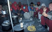 Group of expeditioners at a base camp eating and drinking. 