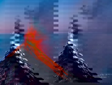 A volcano erupting with lava flowing down the sides