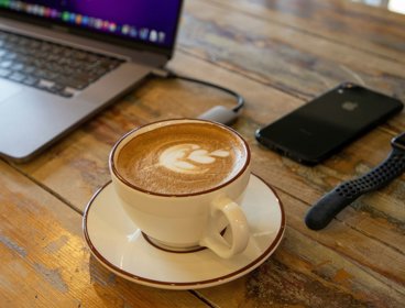 Coffee cup on desk with technology.