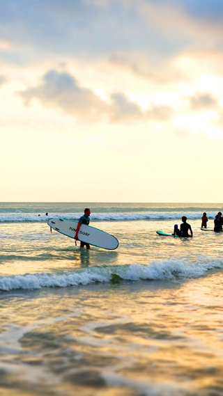 Surfers at the waters edge at sunset