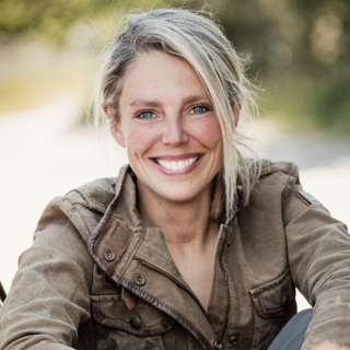 Megan Hine in a brown jacket smiling at the camera.