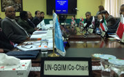 A group of people who are part of a committee sitting around a table and a sign on the table that says United Nations Global Geospatial Information Management co chair.
