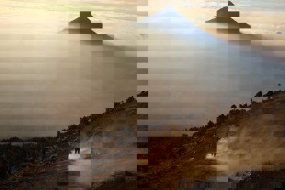 A mountain peak surrounded by cloud and dust