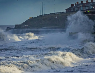 Waves crashing on a shore near coastal residences.