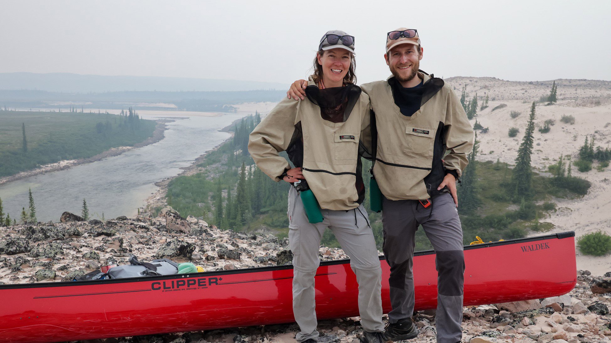Michal and Karolina posing in front of a red canoe on their Barren Lands Expedition