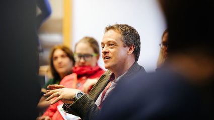 Group of people sitting in a meeting room with one person smiling.