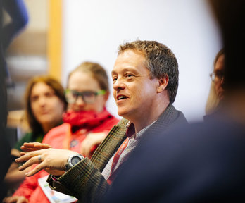 Group of people sitting in a meeting room with one person smiling. 
