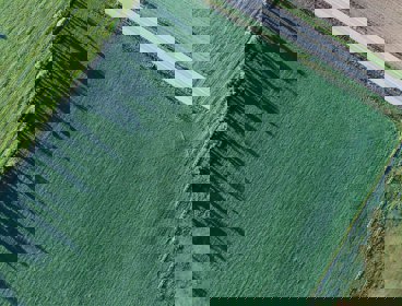 View from above of a road in the countryside passing along a green field.