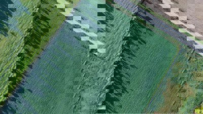 View from above of a road in the countryside passing along a green field.