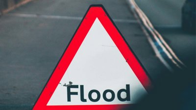 Triangle warning road sign with the word flood on it.