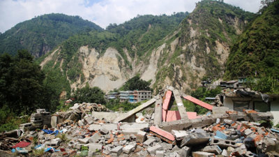 Collapsed buildings surrounded by multiple landslides and rockfalls.