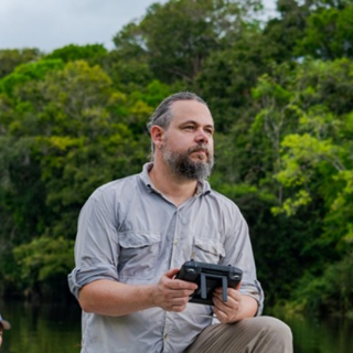 Thiago Silva holding a handheld scanner in a foresty environment.
