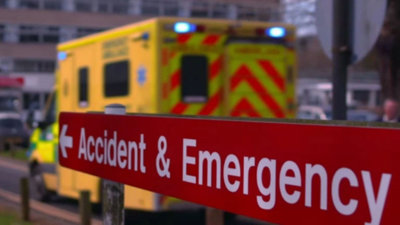 Accident and emergency sign with a blurred out ambulance in the background.
