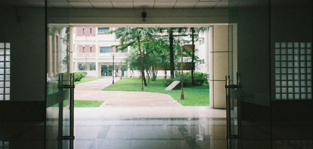 A university campus with open doors leading out to a garden.