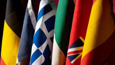 A close-up photo of five different flags positioned next to each other in a row.