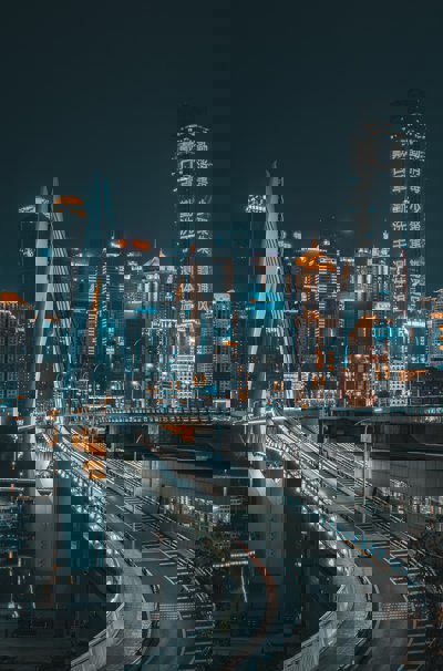 A chinese city at night, with a curving bridge and skyscrapers