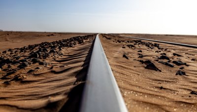 Metal train tracks run trough a rocky desert