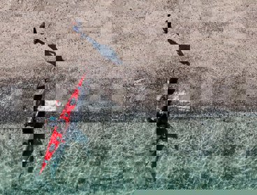 A red kayak in crystal clear blue water seen from above.