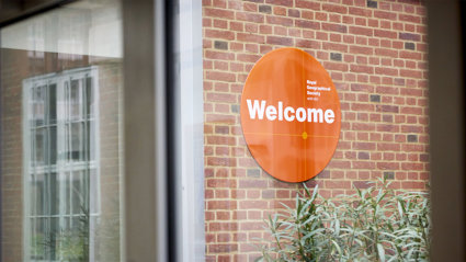 Welcome sign of the Royal Geographical Society (with IBG) seen through a window.