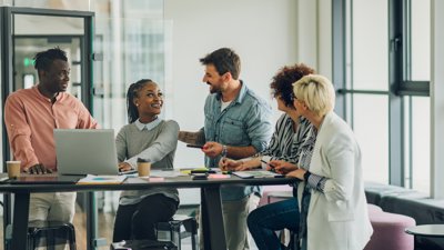 Group of colleagues around a table chatting and smiling