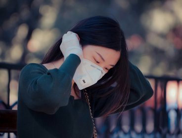 A woman fitting a face mask onto herself