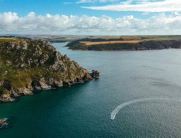 Aerial view of Devon coastline, showing rocky cliffs and green fields.