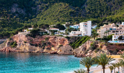 Holiday homes above a small cliff overlooking a bay with blue sea