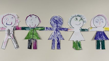 hand-drawn paper dolls coloured with markers, holding hands in a row against a plain background.