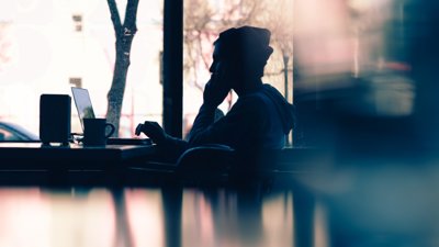Silhouette of a person sitting in front of a laptop