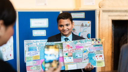 Young school student holding a handmade geography-themed poster.