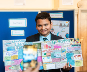 Young school student holding a handmade geography-themed poster.