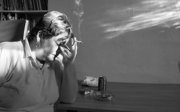 A person resting their head on their hand while holding a cigarette between their fingers.
